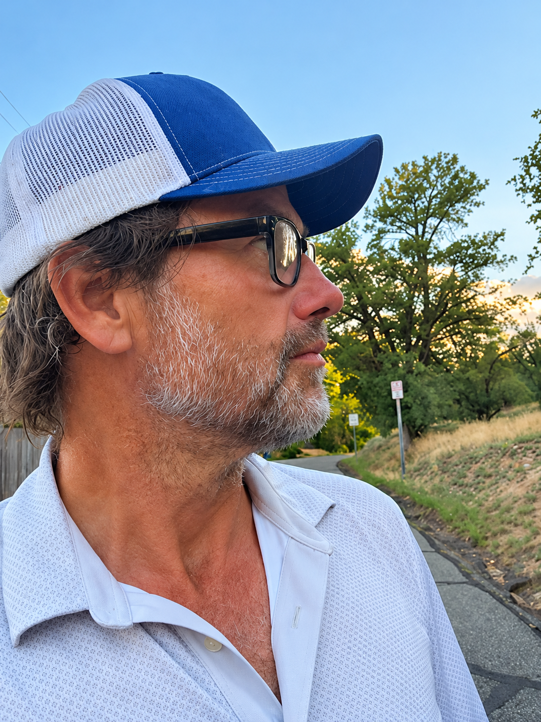 Jerry Zaryczny outdoors in a blue cap, looking thoughtfully toward the trees